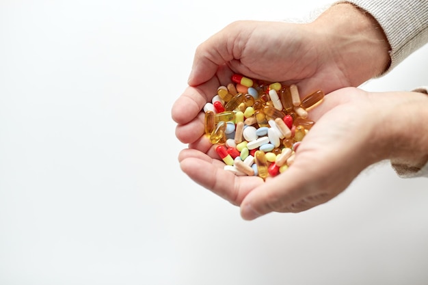 Konzept für Alter, Medizin, Medikamente, Gesundheitswesen und Menschen – Nahaufnahme der Hände eines älteren Mannes, der Pillen hält