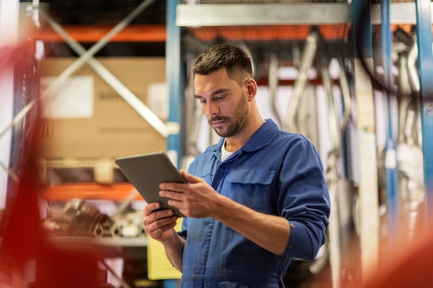 Konzept für Autoservice, Reparatur, Wartung und Personal - Automechaniker oder Schmied mit Tablet-PC-Computer in der Werkstatt oder im Lager