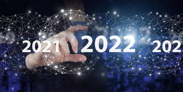 Konzept für das neue Jahr. Hand halten digitales Hologramm 2022 Zeichen auf dunklem, unscharfen Hintergrund der Stadt. Frohes neues Jahr 2022. Konzept für die Vision 2021-2022. Geschäftsmann Willkommensjahr 2022.