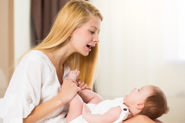 Konzept für Familie, Baby und Elternschaft. Glücklich lächelnde junge Mutter mit Säuglingsbaby zu Hause verbringen Zeit zusammen