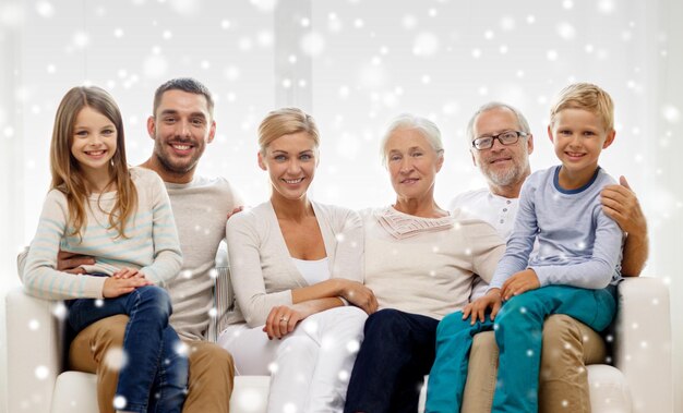 Foto konzept für familie, glück, generation und menschen - glückliche familie, die zu hause auf der couch sitzt