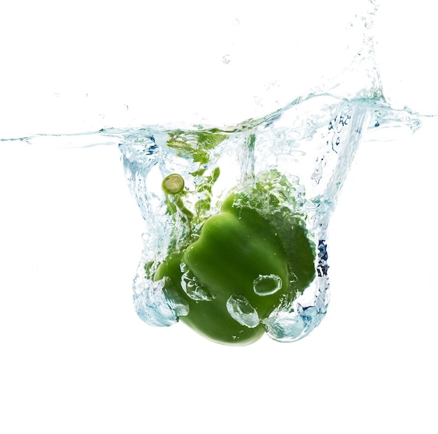 Konzept für Gemüse, Lebensmittel und gesunde Ernährung - Nahaufnahme von frischem grünem Pfeffer, der mit Spritzer auf weißem Hintergrund in Wasser fällt oder eintaucht