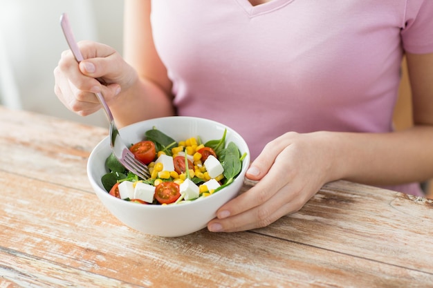 Konzept für gesunde ernährung, diät und menschen - nahaufnahme einer jungen frau, die zu hause gemüsesalat isst