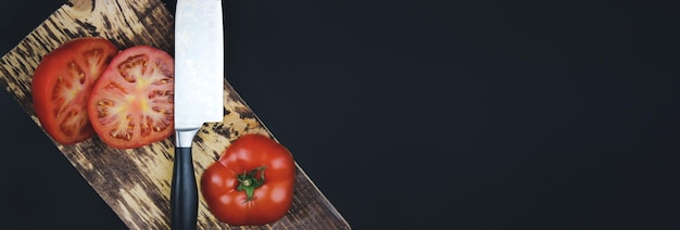 Konzept für gesunde Ernährung Draufsicht Kopierbereich Frische Tomaten auf Schneidebrett in dunklem Hintergrund