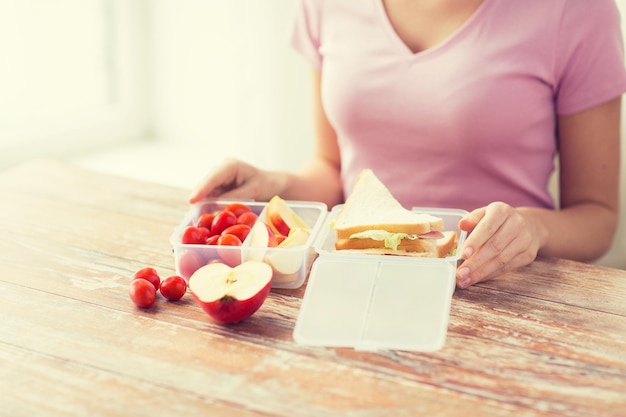 Konzept für gesunde Ernährung, Lagerung, Diät und Menschen - Nahaufnahme einer Frau mit Lebensmitteln in Plastikbehältern in der Küche zu Hause