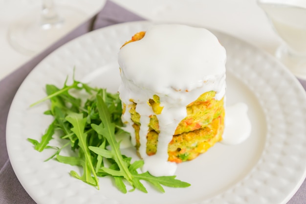 Konzept für gesunde Ernährung. Leckeres Gemüseschnitzel aus Karotten, Zucchini, Mais und Erbsen mit weißer Sauce und einem Glas Orangensaft