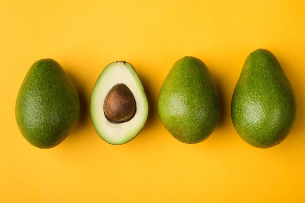 Konzept für gesunde Ernährung. Oben über dem Overhead-Nahaufnahmefoto der geschnittenen Avocado isoliert auf gelbem Hintergrund