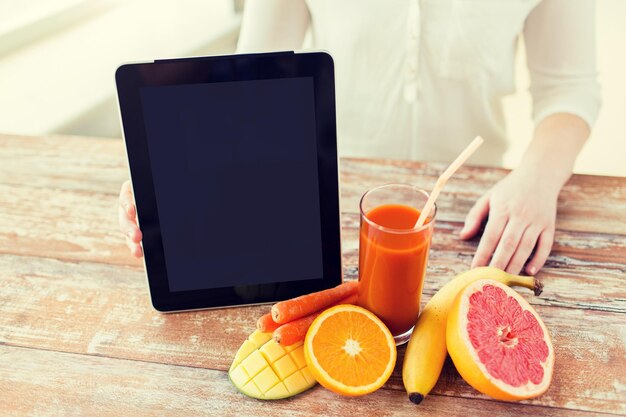 Foto konzept für gesunde ernährung, technologie, ernährung und menschen - nahaufnahme von frauenhänden mit tablet-pc, obst und frischem saft am tisch