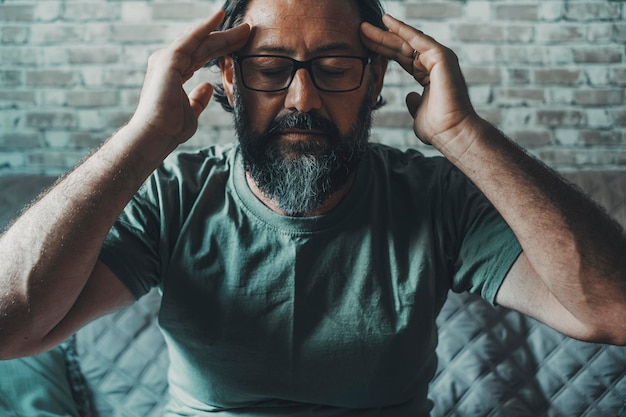 Konzept für Menschen mit psychischer Gesundheit Ein erwachsener Mann zu Hause berührt seine Schläfen und denkt nach einer Lösung Menschen und Meditation gesunder Lebensstil Konzept von Gedanken und Lebensschwierigkeiten Kopfschmerzen Schmerzen