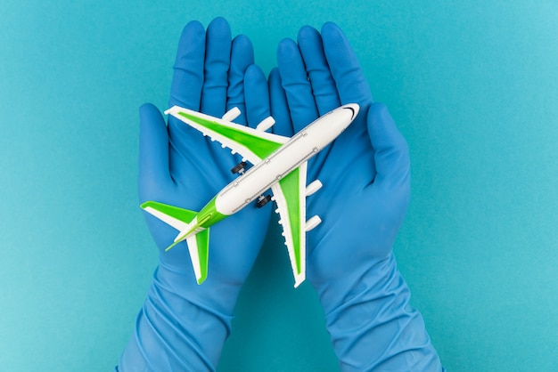 Konzept für sicheres Reisen. Flugzeug in Händen in medizinischen Handschuhen. Sicherheitsflug und Reise während Quarantäne und Sperrung.