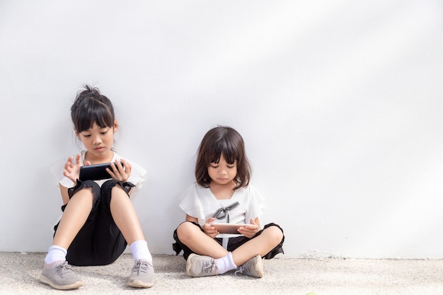 Konzept Kinder und Gadgets Zwei kleine Mädchen Geschwister Schwestern schauen auf das Telefon