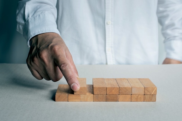 Konzept Plan und Strategie im Geschäft mit einem Holzblock. Der Mann hat einen Holzblock auf den Tisch gelegt. Erfolg des Geschäftskonzeptwachstums