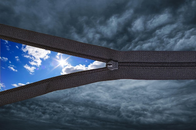 Konzept schwarze Donnerwolken mit Reißverschluss und sonniger blauer Sommerhimmel mit Wolken im HintergrundWetter ändern