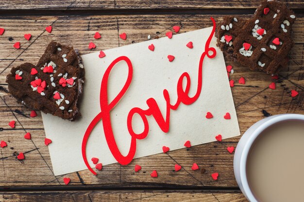 Konzept Valentinstag. Tasse Kaffee und Kekse auf einem Holztisch. Grußkarte.