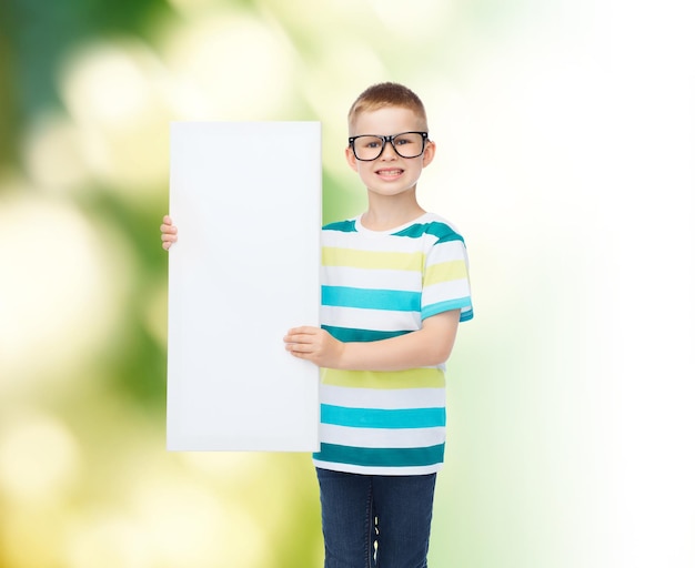 Konzept Vision, Gesundheit, Werbung, Ökologie und Menschen - lächelnder kleiner Junge mit Brille mit weißem, leerem Brett auf grünem Hintergrund