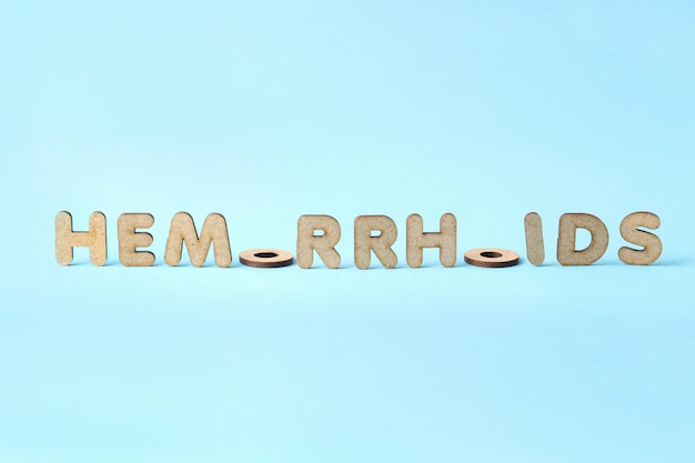 Konzept von Hämorrhoiden mit Holzbuchstaben auf blauem Hintergrund