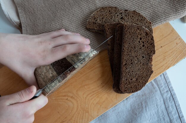 Konzept von hausgemachtem brot, natürlichen landwirtschaftlichen produkten, einheimischer produktion. gesunde und leckere bio-lebensmittel. frau, die frisch gebackenes vollkornbrot schneidet.