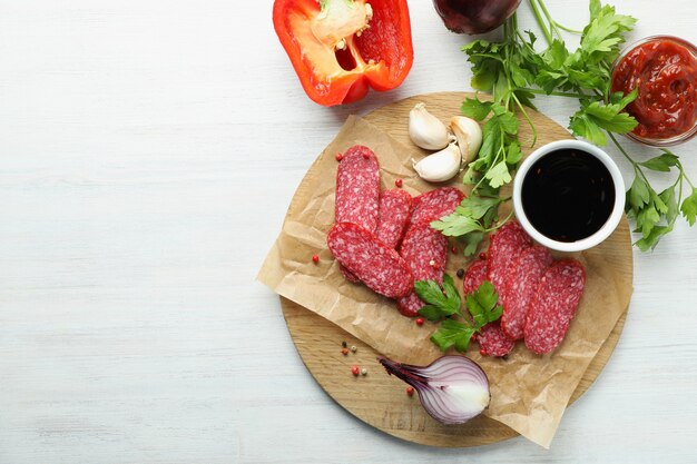 Ã Konzept von leckerem Essen mit Salamiwurst auf weißem Holzhintergrund