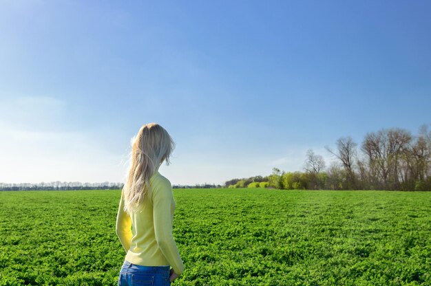 Konzept von Tourismus und Erholung. Frauentourist auf grünem Gras auf einer Wiese mit Blick in die Ferne