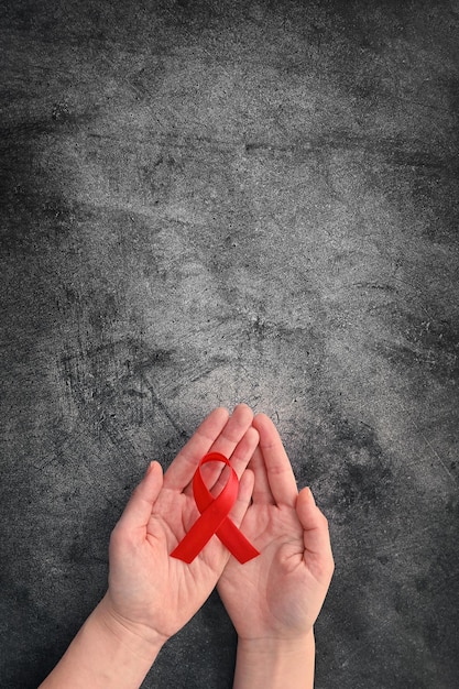 Konzept Welt-AIDS-Tag Hände der Frau mit rotem Band auf schwarzem Hintergrund Bluttransfusion