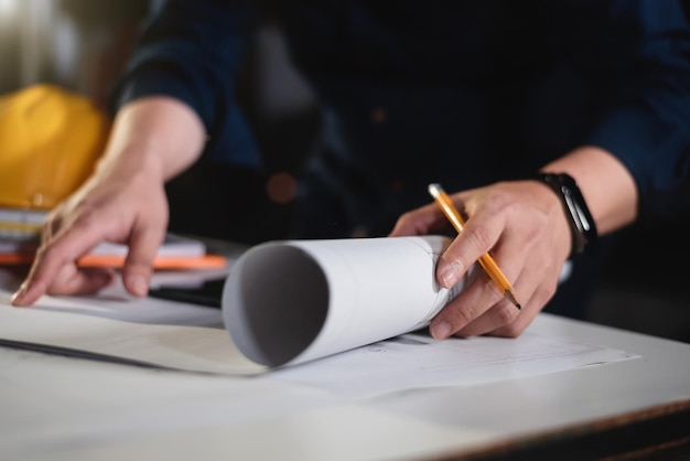 Konzeptarchitekten oder Ingenieure, die auf dem Schreibtisch mit einem Entwurf im Büro einen Stift zeigen, der Ausrüstungsarchitekten zeigt