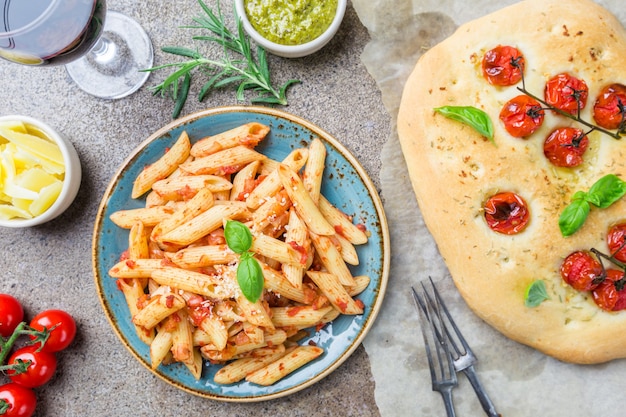 Konzepte von Penne-Nudeln mit italienischem Essen in Tomatensauce und Focaccia-Brot-Draufsicht