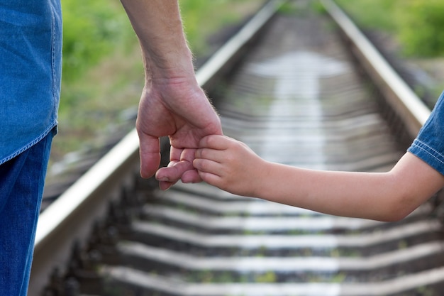 Konzepteltern halten die Hand eines kleinen Kindes und Eisenbahn und Richtung