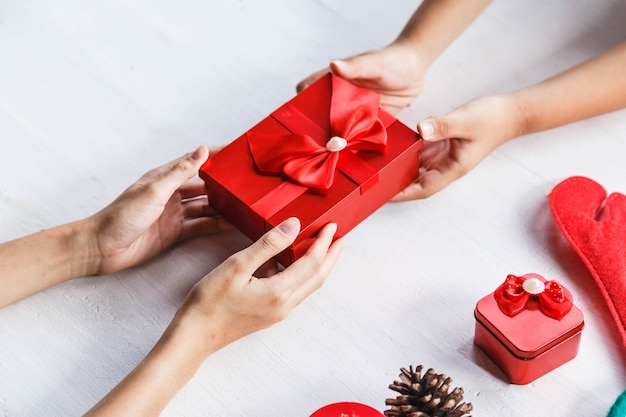 Konzeptideen des Weihnachtstages mit Hand der jungen Person, die Geschenkboxdekoration gibt