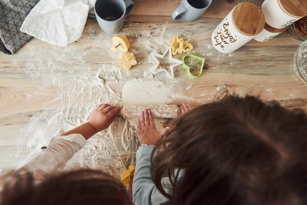 Konzeption des Kochens. Draufsicht von den Kindern, die lernen, Lebensmittel vom Mehl mit speziell geformten Instrumenten zuzubereiten