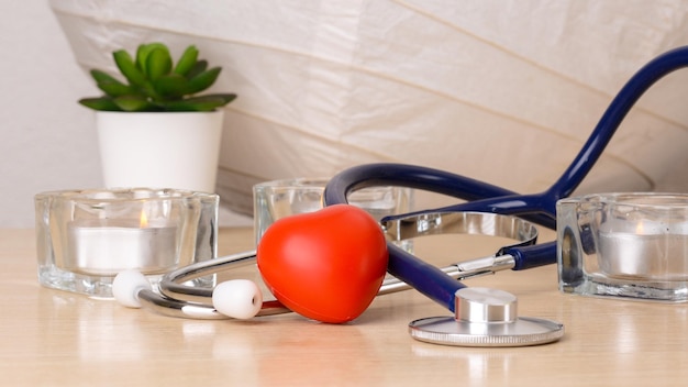 Konzeptstethoskop und rotes Herz mit Krankenversicherungsinstrument zur Überprüfung des Herzens auf weißem Hintergrund