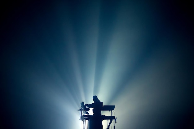 Konzert mit elektronischer Musik. Musiker auf der Bühne in Licht- und Rauchstrahlen