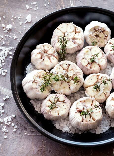 Kopf aus frischem Knoblauch mit Kräutern und Salz Knoblauch bereit zum Rösten Draufsicht Vertikales Foto