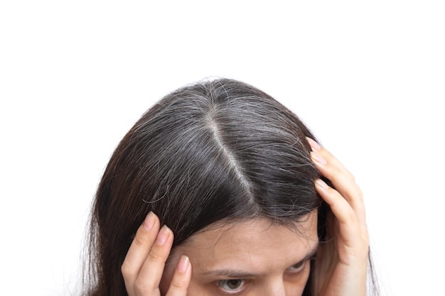 Kopf einer Frau mit ergrauendem Haar auf weißem Hintergrund. Das Konzept der frühen grauen Haare.