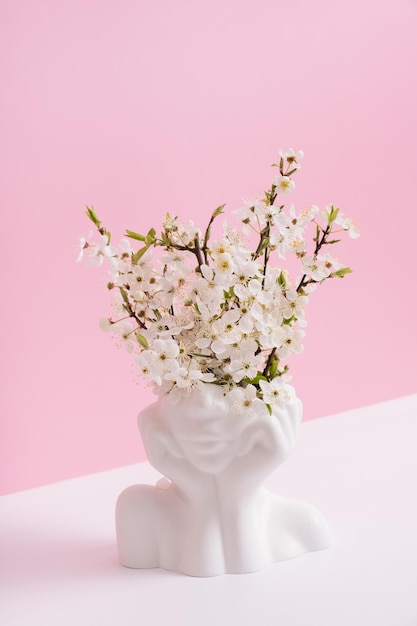 Kopfform-Vase mit Frühlingsblüte auf rosa Hintergrund Frühlingsinspiration psychisches Gesundheitskonzept