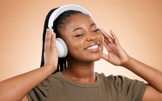 Kopfhörermusik und afrikanische Frau isoliert auf Studiohintergrund für Energie- und Wellness-Podcast für psychische Gesundheit Fröhliche, ruhige schwarze Menschen, die Audio mit einem Lächeln im Gesicht für stressfreien Sound hören