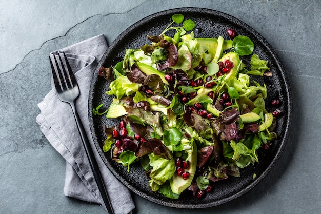 Kopfsalatsalat mit Granatapfel auf Schwarzblech. Ansicht von oben