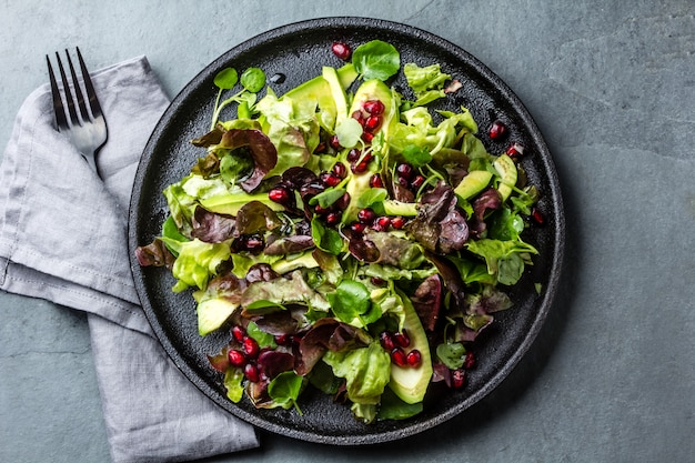 Kopfsalatsalat mit Granatapfel auf Schwarzblech. Ansicht von oben