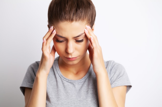 Kopfschmerzen, erschöpfte junge Frau hat unter unerträglichen Kopfschmerzen