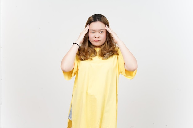 Kopfschmerzen-Geste der schönen asiatischen Frau, die gelbes T-Shirt lokalisiert auf weißem Hintergrund trägt