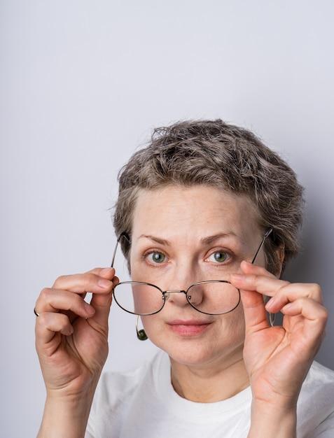 Kopfschuss einer offen aussehenden grauhaarigen Frau mit Brille