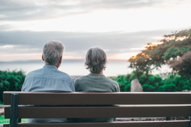 Kopfschuss Nahaufnahme Porträt glückliche grauhaarige Frau mittleren Alters mit älterem Ehemann, die es genießt, auf der Bank im Park zu sitzen Bindung liebevolles altes Familienpaar, das den Sonnenuntergang umarmt