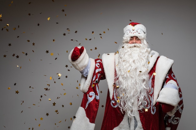 Kopfschuss von Santa Claus in rotem Hut, grauhaariger, müder Mann auf grauem Studiohintergrund. Foto in hoher Qualität