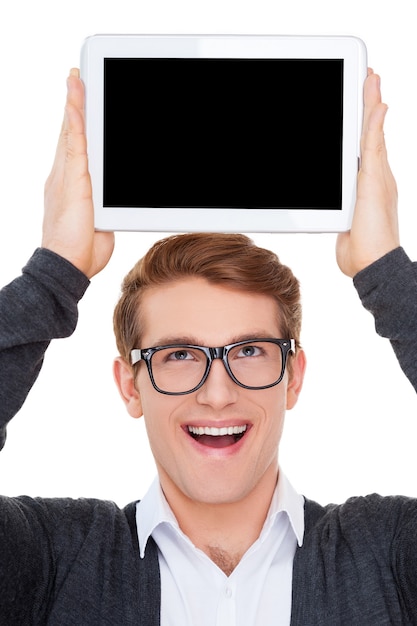 Foto kopieren sie platz auf seinem tablet. fröhlicher junger mann, der ein digitales tablet auf dem kopf hält und lächelt, während er isoliert auf weiß steht