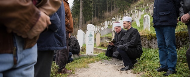 koran heiliges buch lesen durch imam auf islamischer beerdigung mit weißen daumensteinen graweyard hintergrund