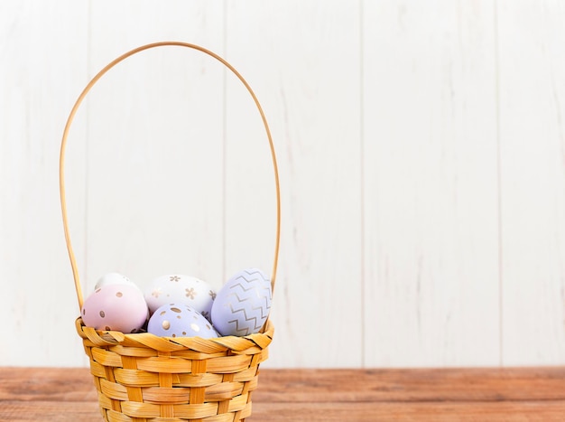 Korb mit bunten Ostereiern auf einem Holztisch