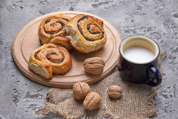 Korb mit hausgemachten Brötchen mit Marmelade, serviert auf einem alten Holztisch mit Walnüssen und einer Tasse Milch