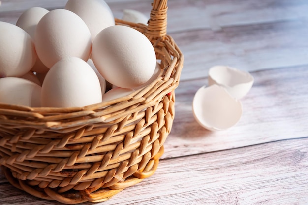 Korb mit weißen Eiern Weiße Eier in einem Weidenkorb Gebrochene Eierschalen neben ganzen Eiern Einfache Zusammensetzung