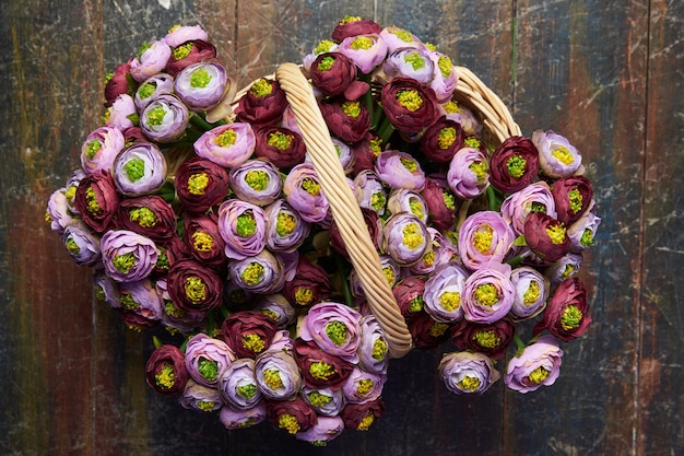 Korb voller Pfingstrosen lila rosa und weinroter Korb mit Griff steht auf dem Holzboden