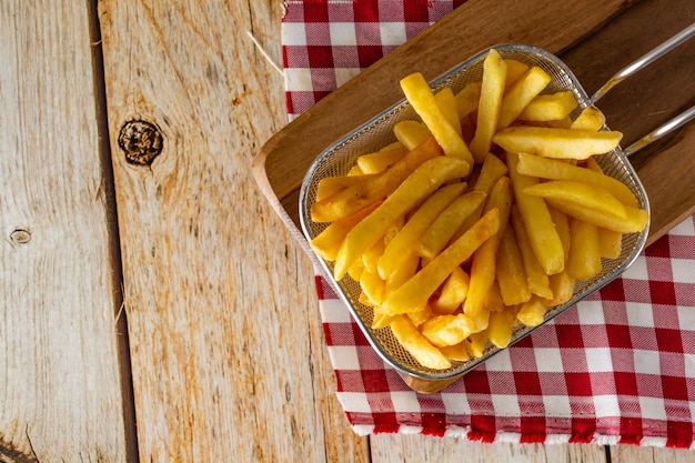 Korb voller Pommes Frites auf rustikalem Holztisch