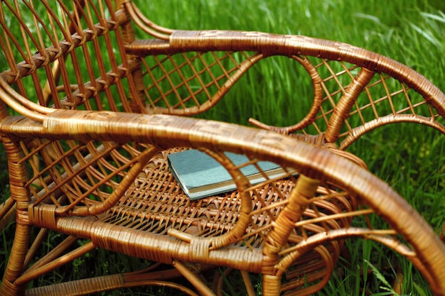 Korbschaukelstuhl mit Buch im Garten